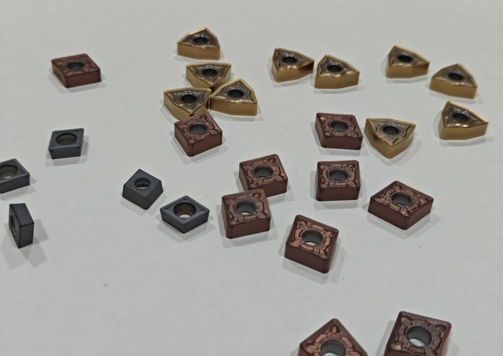 Collection of CNC turning carbide inserts showing different ISO shapes and coatings